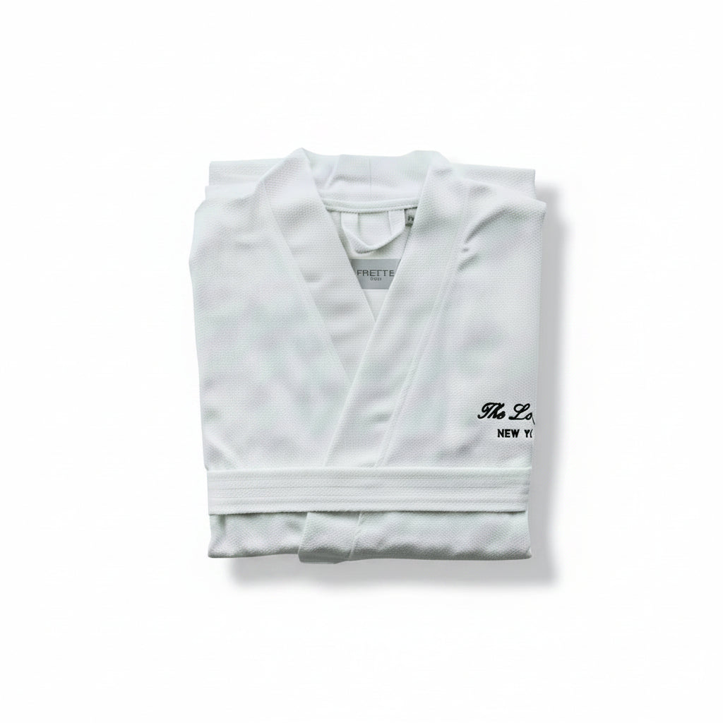 A folded white robe with a black embroidered logo reading